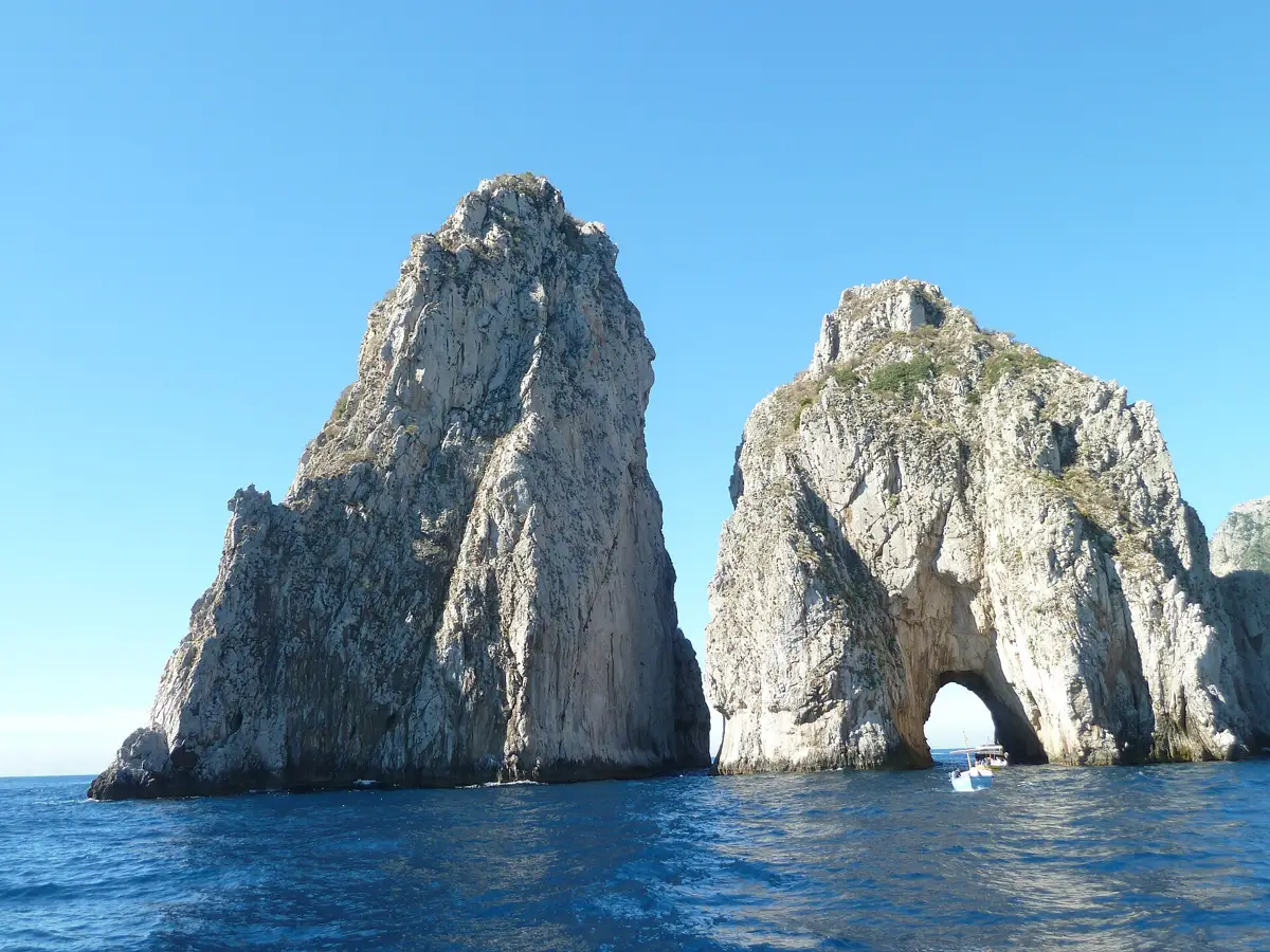 The Faraglioni sea stacks off Capri with a small boat passing the natural arch