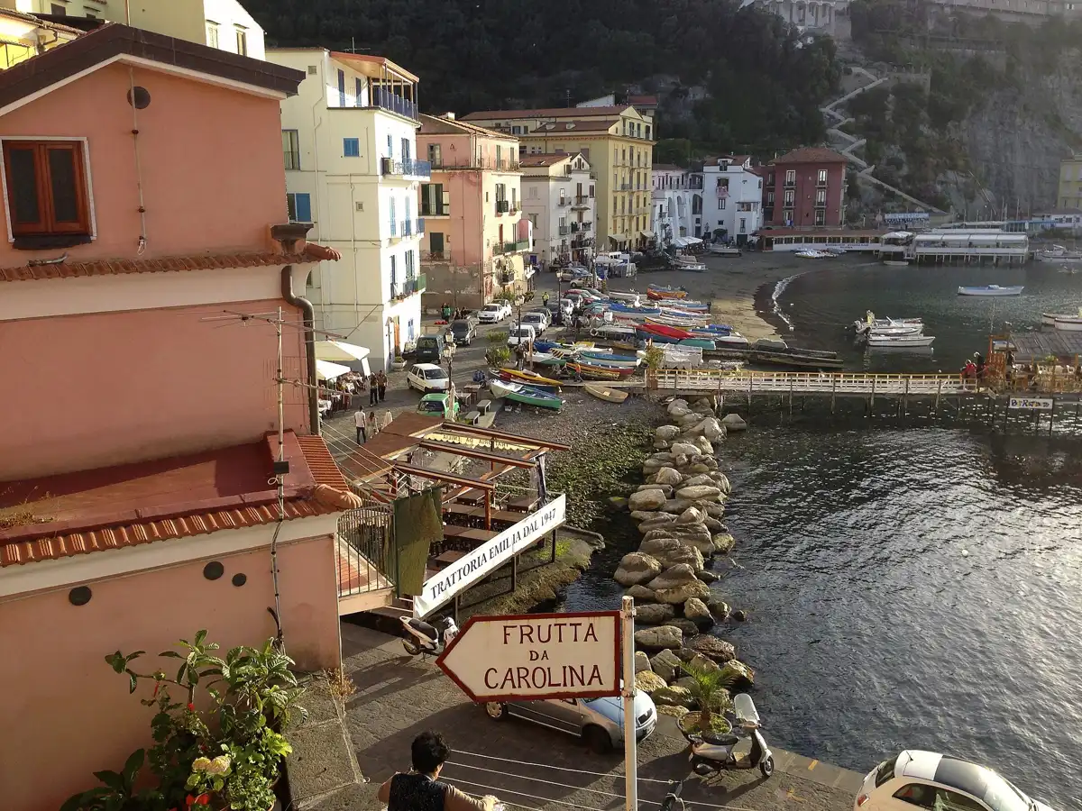 Marina Grande harbour in Sorrento at sunset with painted boats and the village houses above
